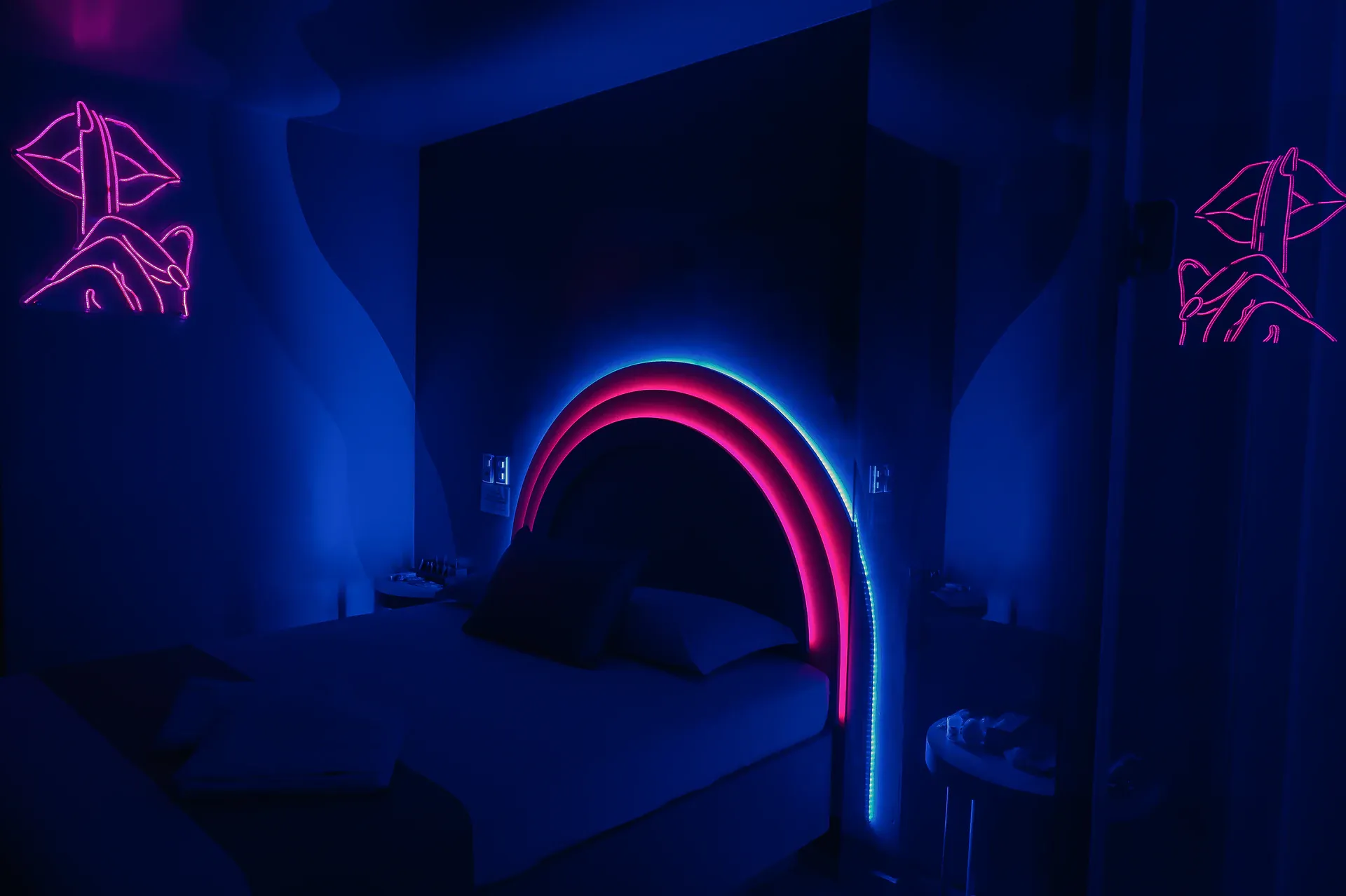 Cama da Suíte Luxo emoldurada por arco de neon azul e rosa