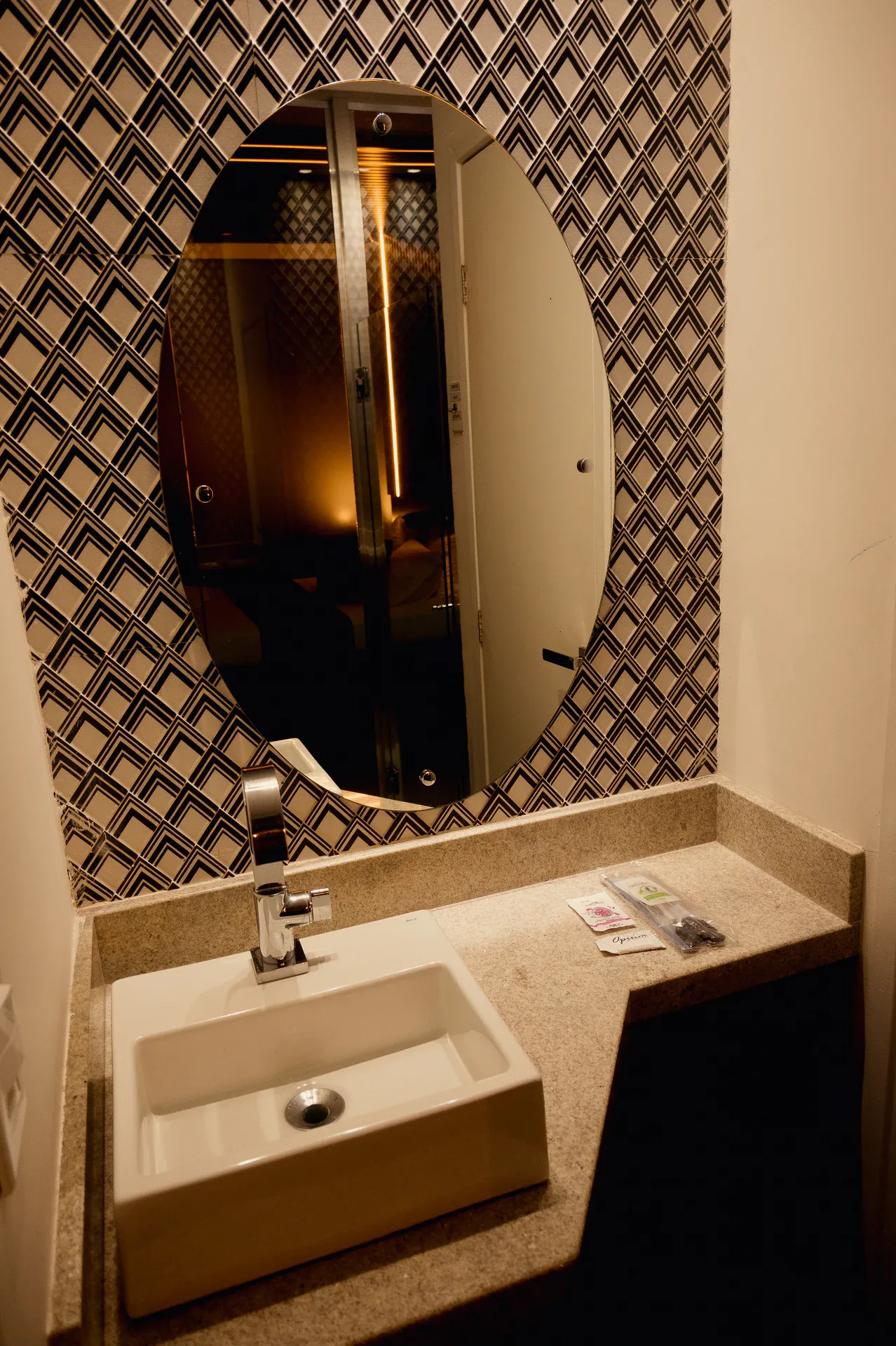 Lavabo da Suíte Luxo com espelho oval e revestimento geométrico preto e branco