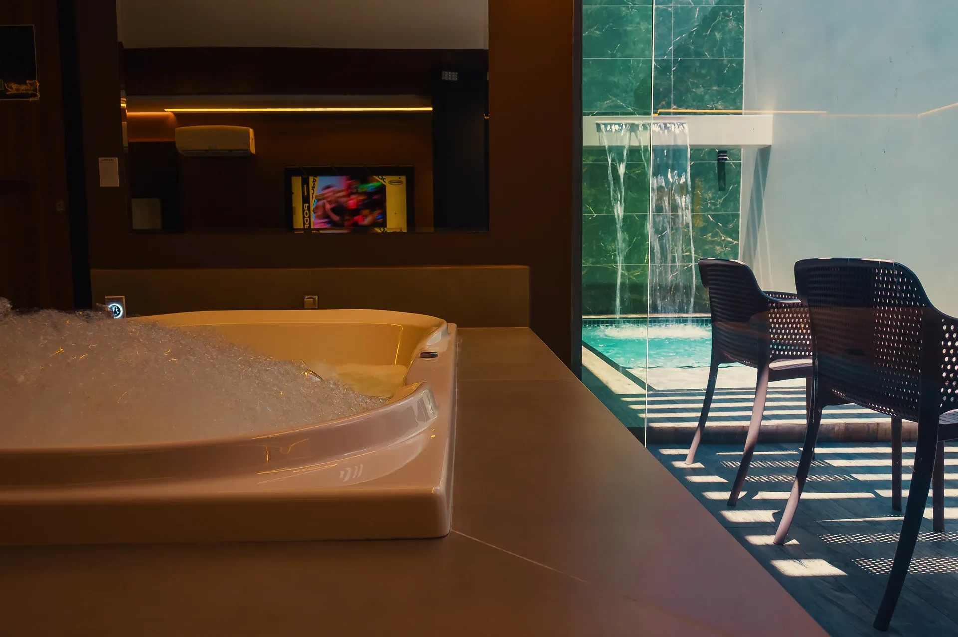 Hidromassagem interna ao lado da piscina com cascata da Suíte Opium