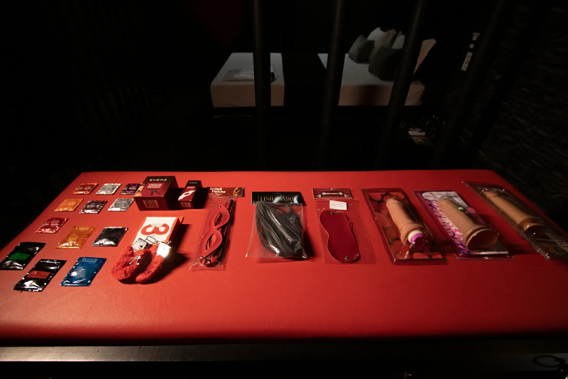 Detalhe da Suíte Sado com banco vermelho e itens da boutique íntima